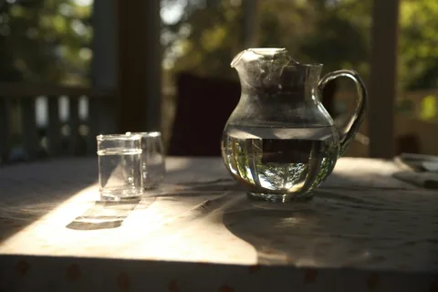 Glass water pitcher and drinking glass on a table